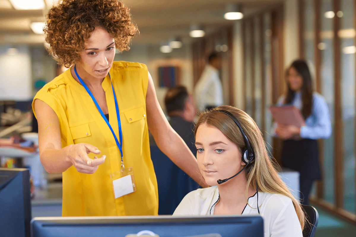 instructor helping a female student working in customer service