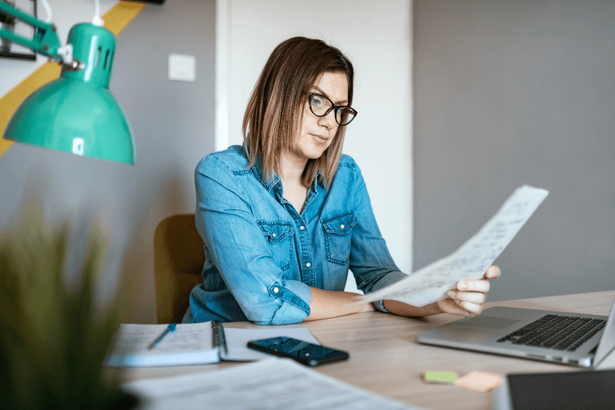 young woman sitting at an office desk reviewing paperwork