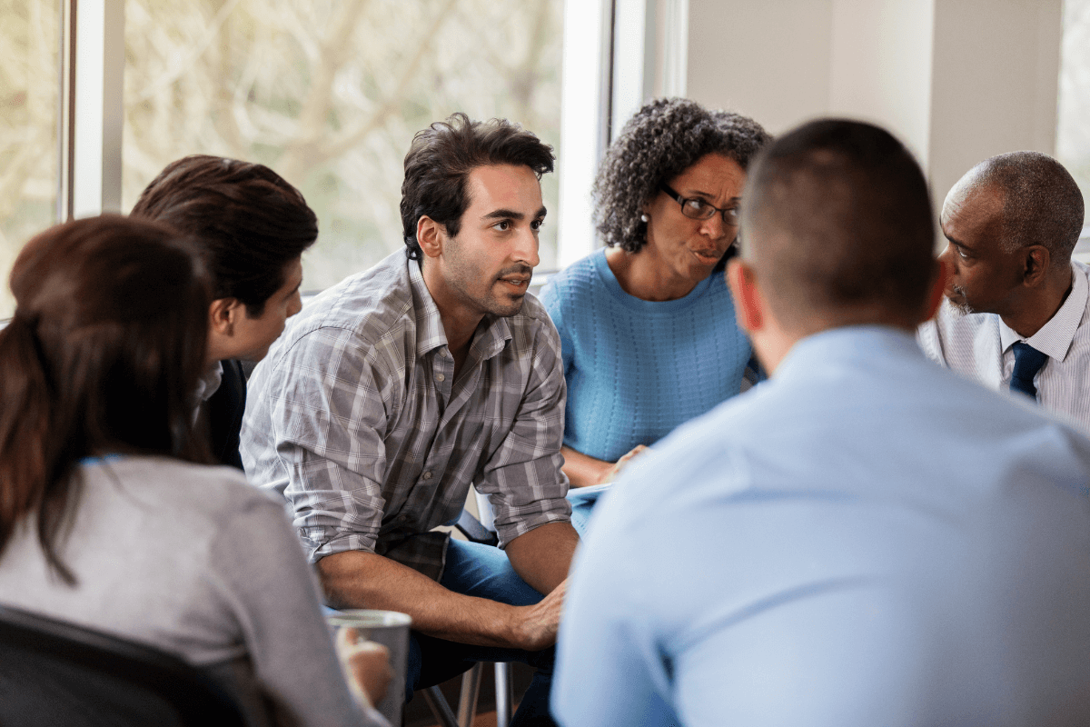 group of adults sitting in a circle in a meeting room