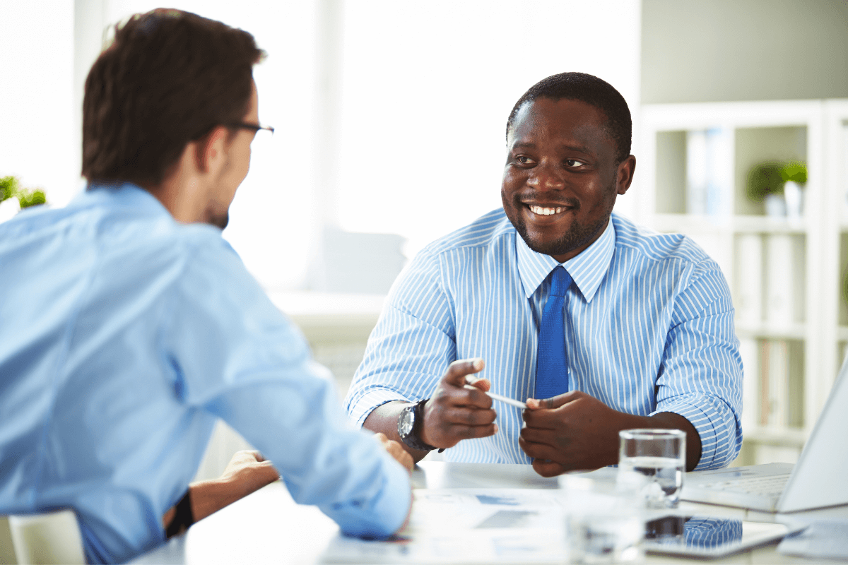 two men in business attire sitting at a table talking