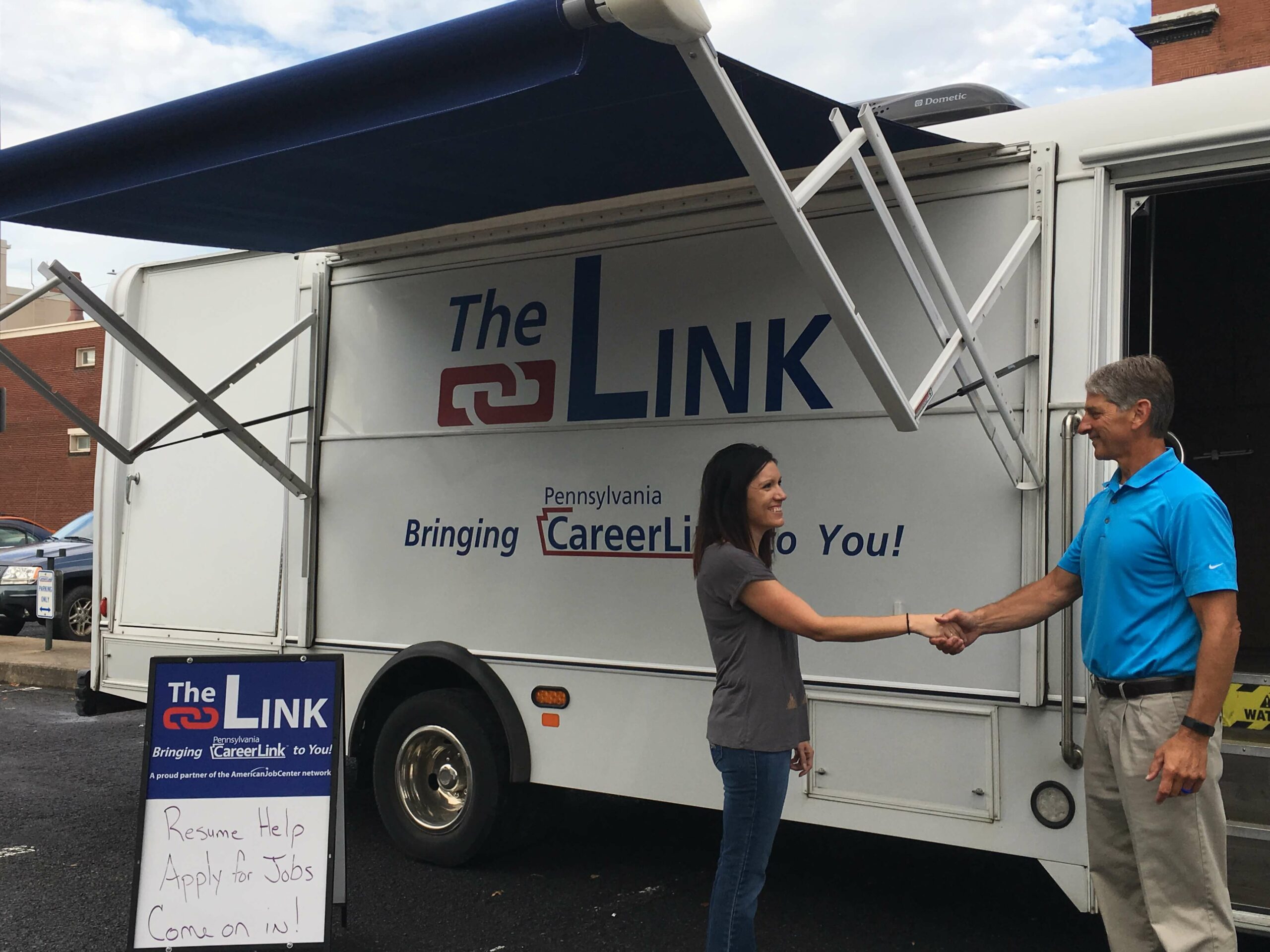 two adults shaking hands outside The Link mobile workforce center