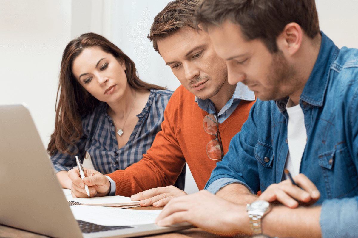 close up of two men and a woman working at a laptop