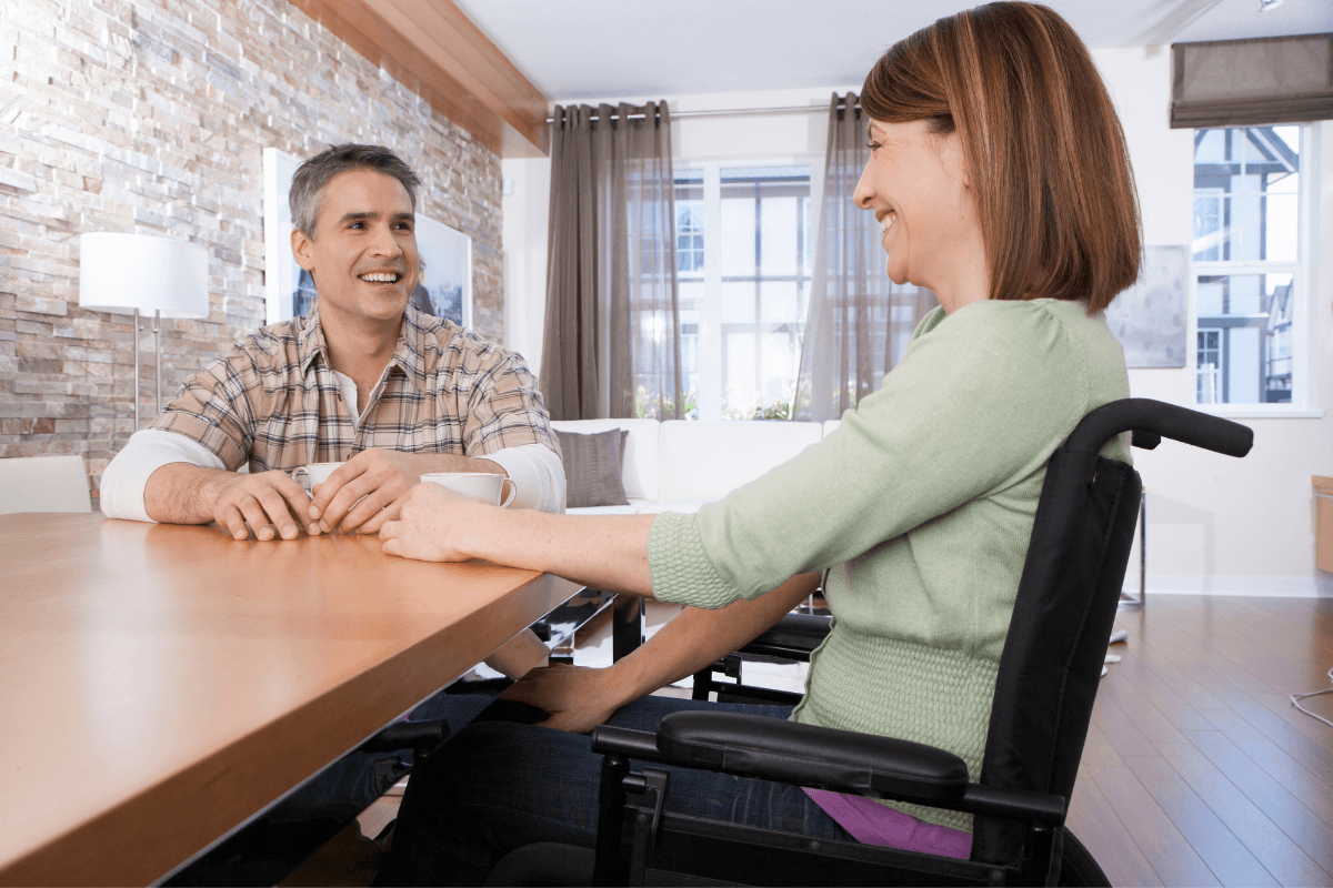 young woman in a wheelchair talking to a man sitting at a desk