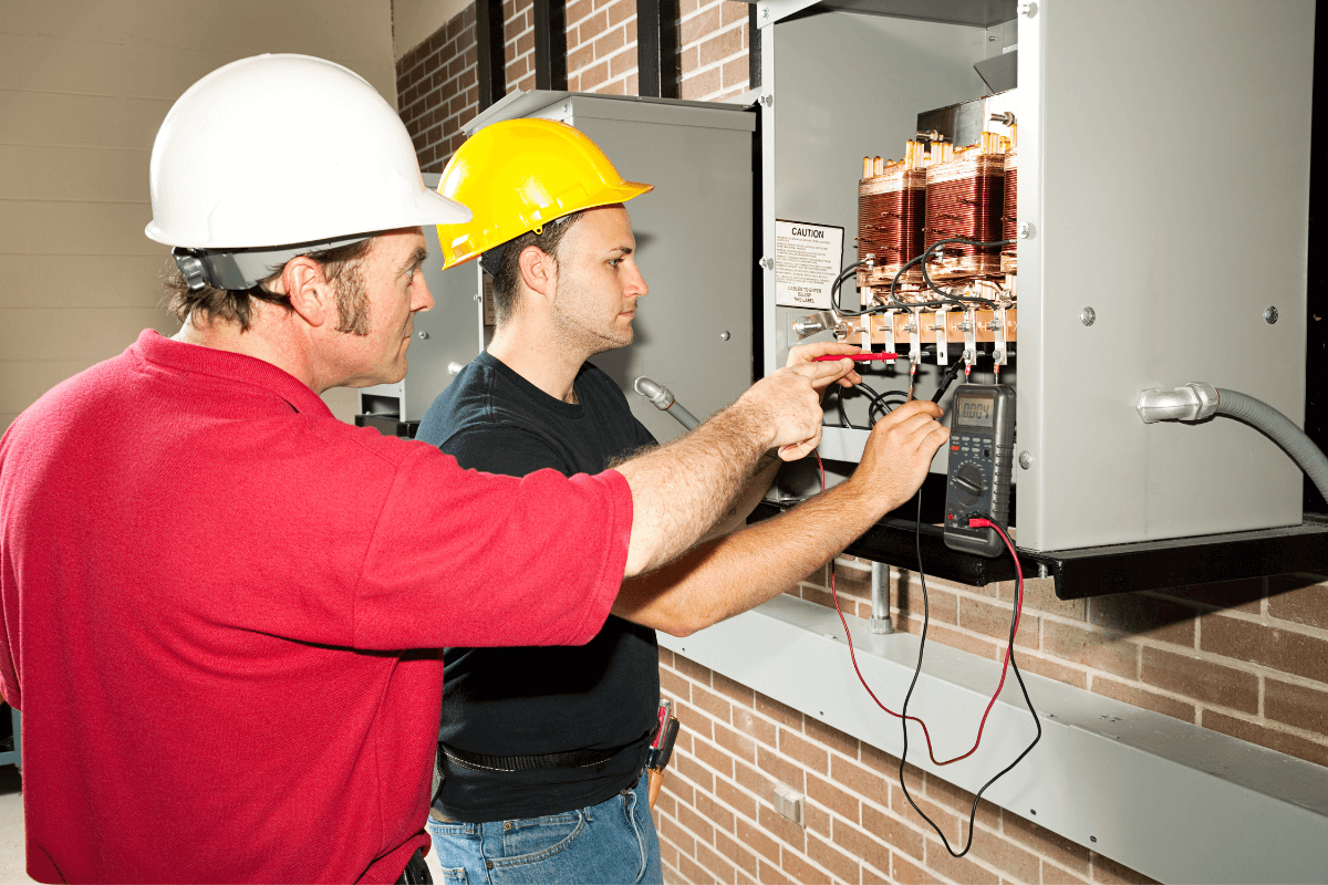 two male workers looking at a electric utility box